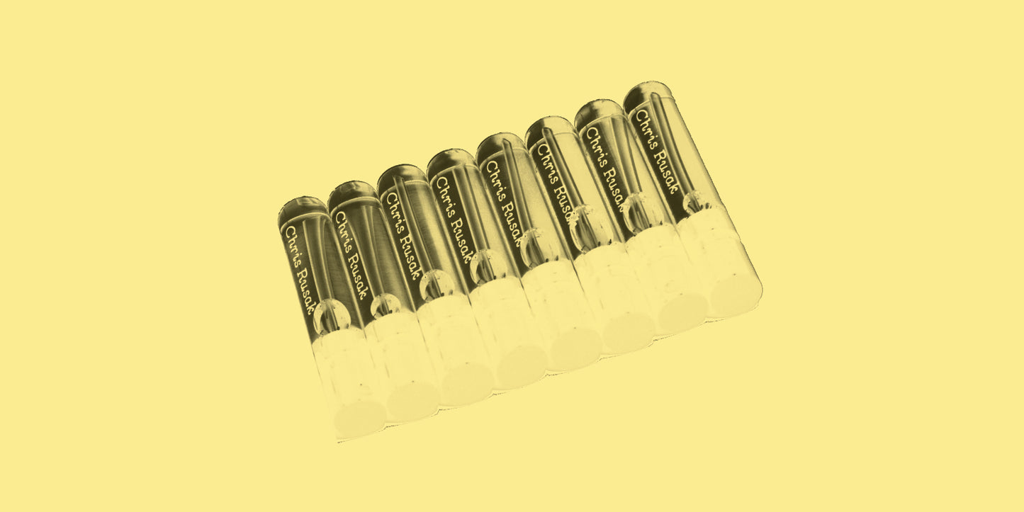 Desaturated photo of a group of perfume sample vials on a pale background